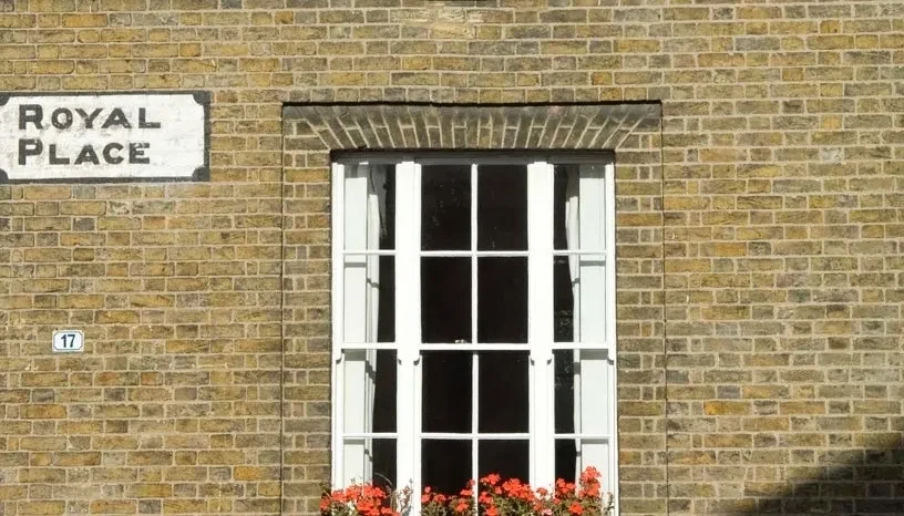 A window in a brick wall, with a street sign, 'Royal Place'.