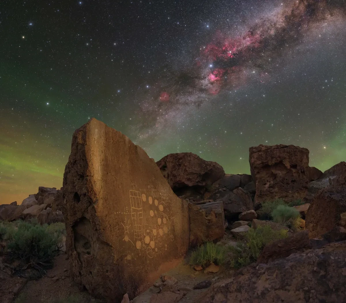 Rock carved with ancient markings in foreground with vivid Milky Way in purples and dark colours in sky above