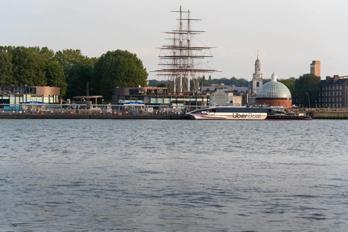 A photograph of the quayside at Greenwich, with a modern ferry service moored in front of the historic ship Cutty Sark