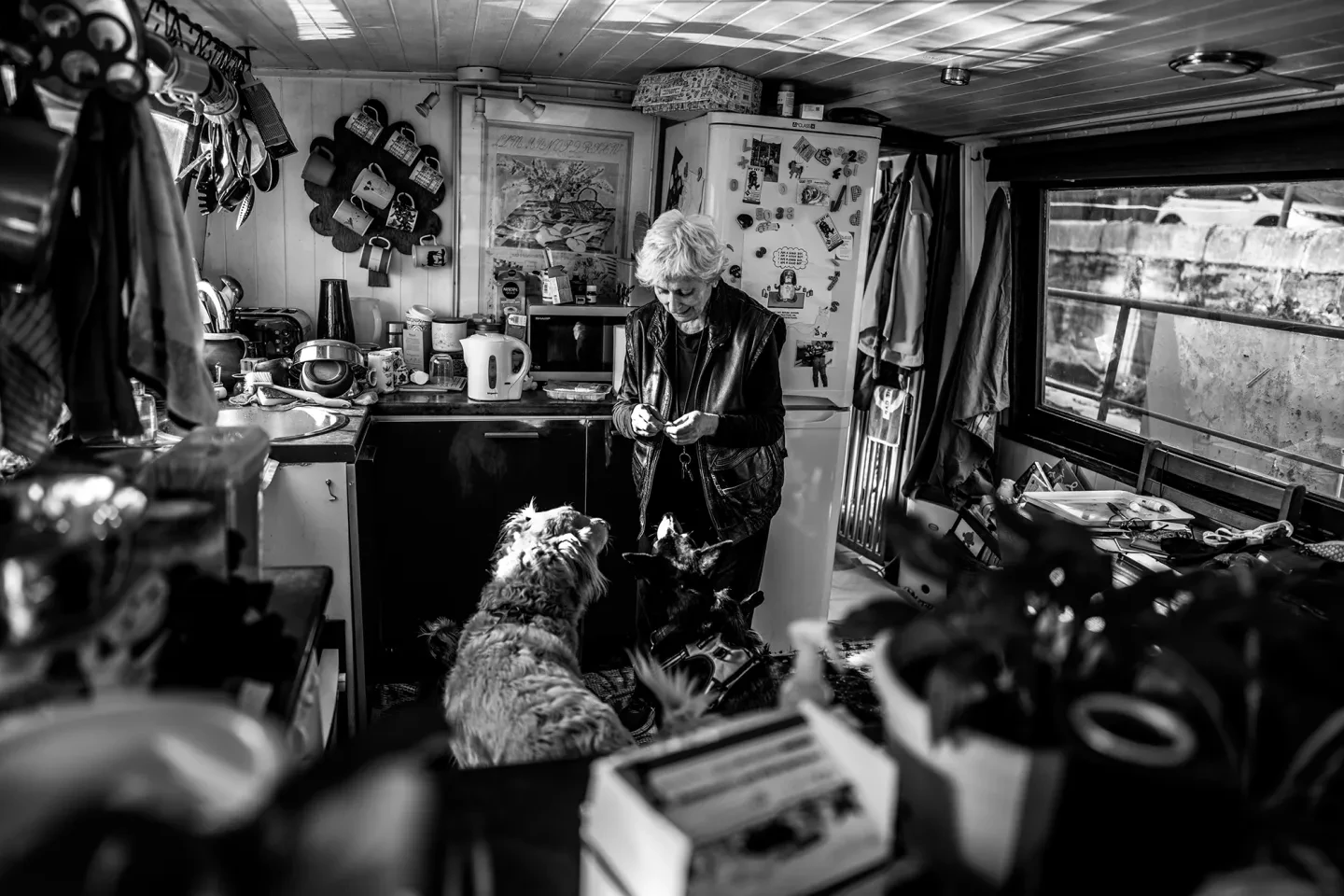 A woman feeds a dog in a houseboat