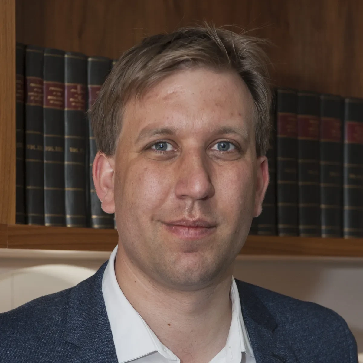 Photograph of Chris Lintott, smiling, wearing white shirt and navy jacket.