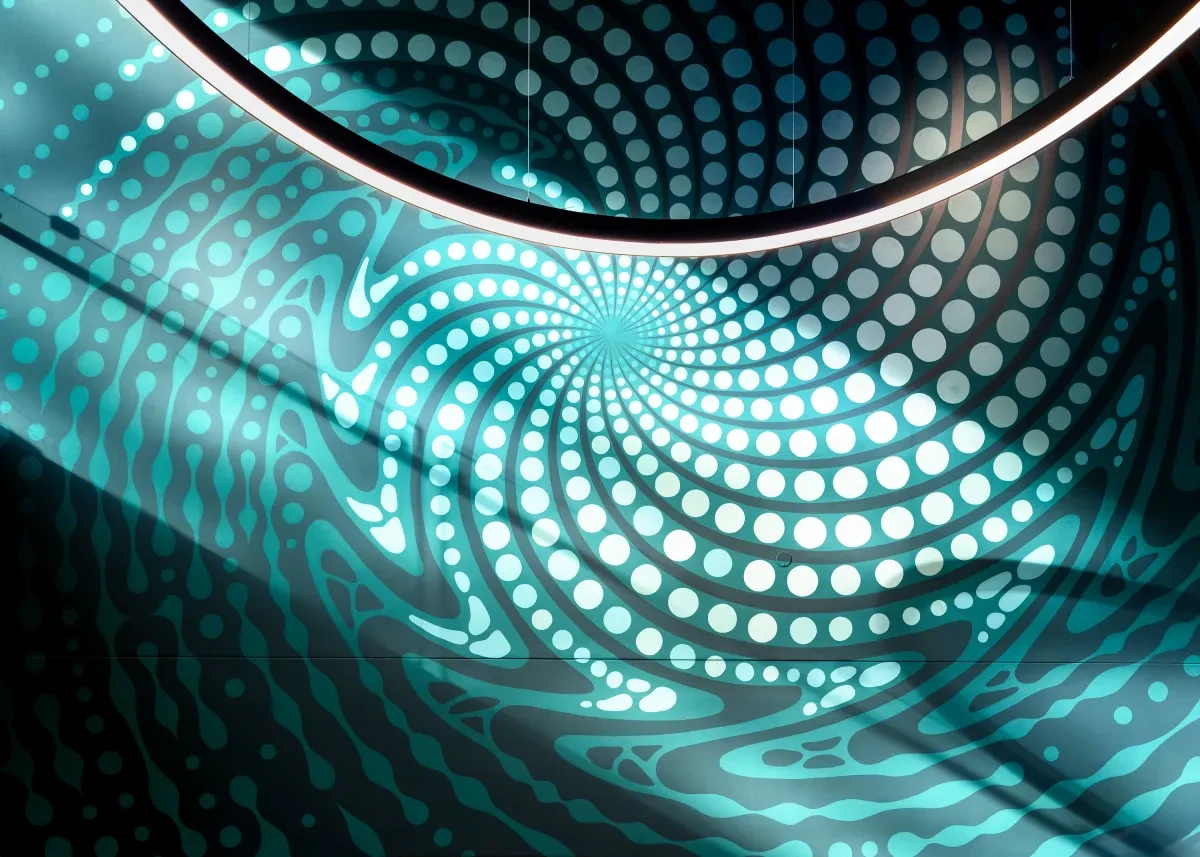 Close-up view of a wall mural, showing a swirling pattern of dots on a turquoise blue background