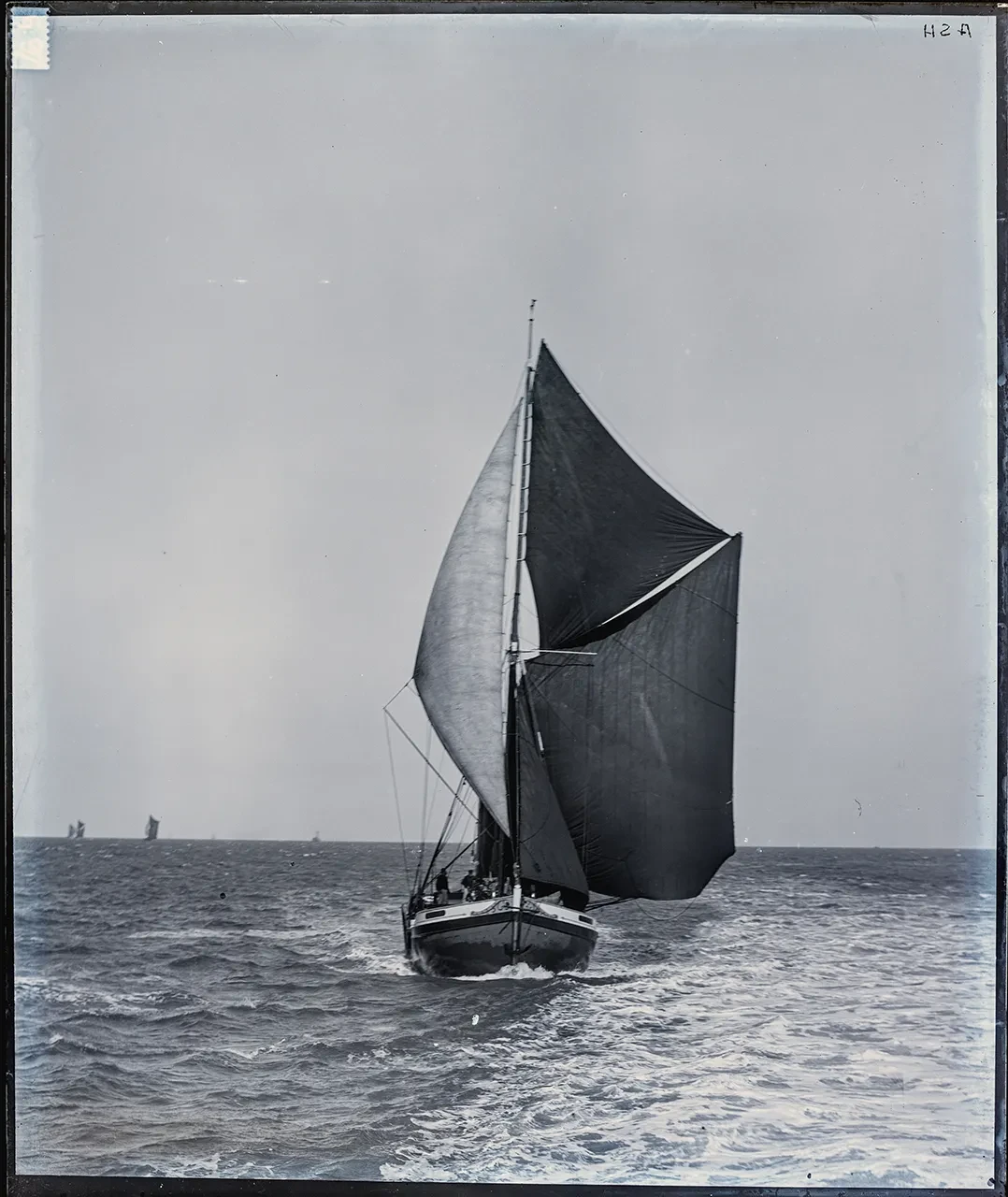 Black and white glass plate photograph of a Thames sailing barge. The ship is at sea and approaching the photographer