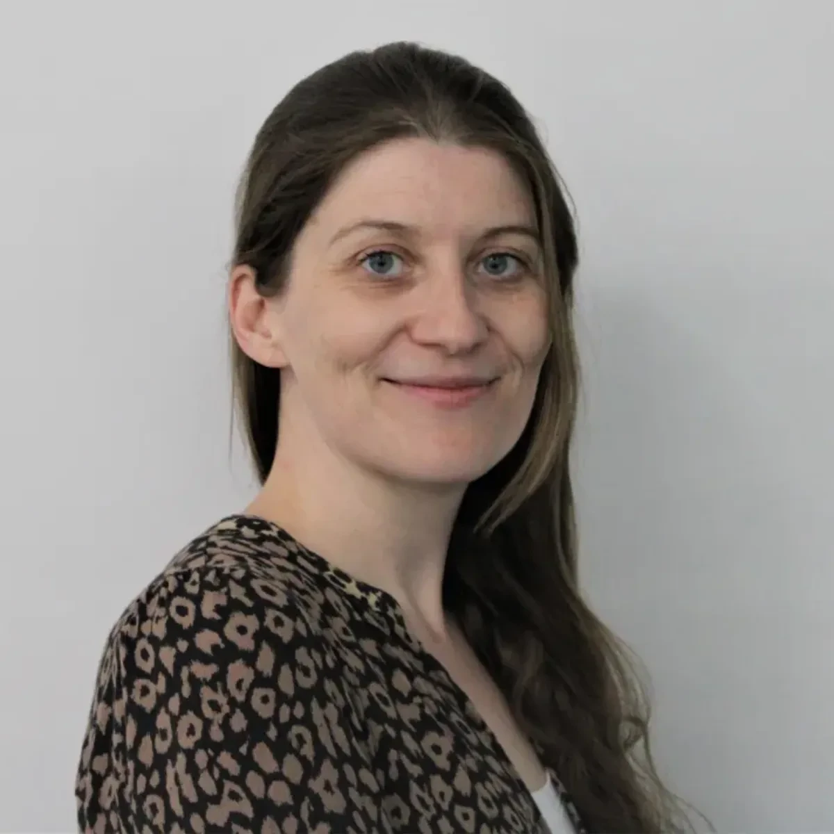 Headshot of museum curator Laura Boon-Williams. She has medium-length brown hair and grey-blue eyes, and is turning to smile at the camera