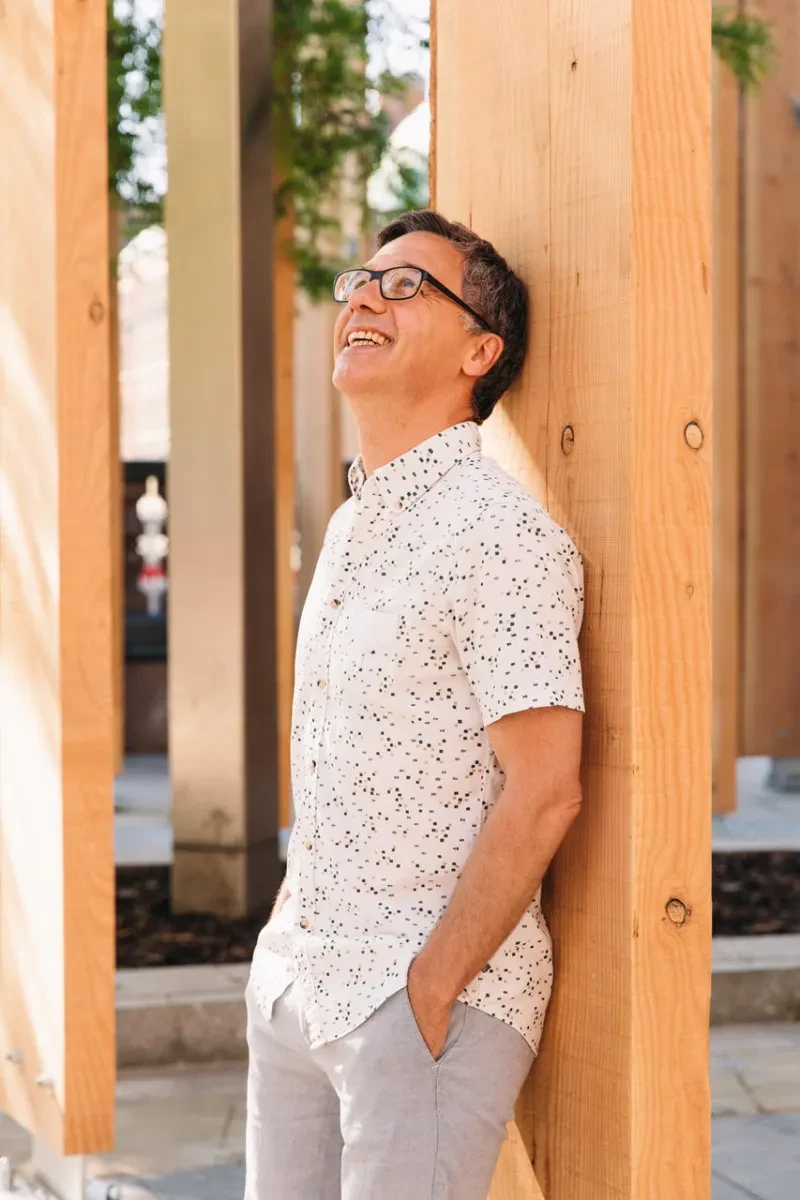 Headshot of Michael Pinsky against a wooden structure staring at the sky