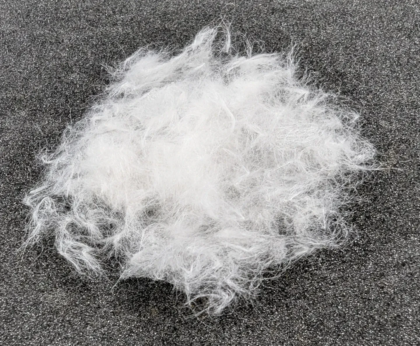 A pile of white, fluffy strands of paper laid out on a grey tabletop
