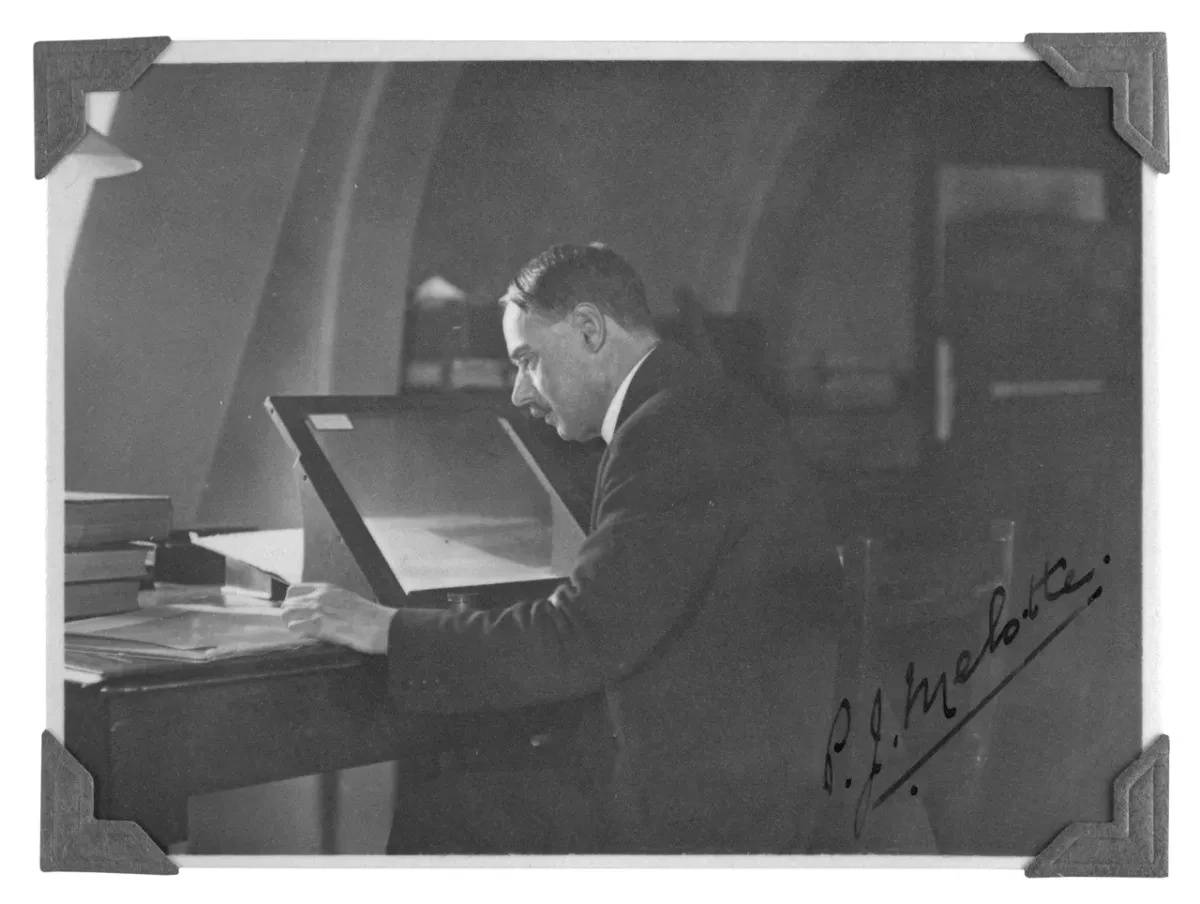 Old black and white photo of P.J Melotte sitting and looking at photographic plate