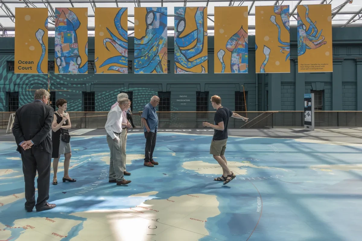 A group of people stand on the new Ocean Map at the National Maritime Museum