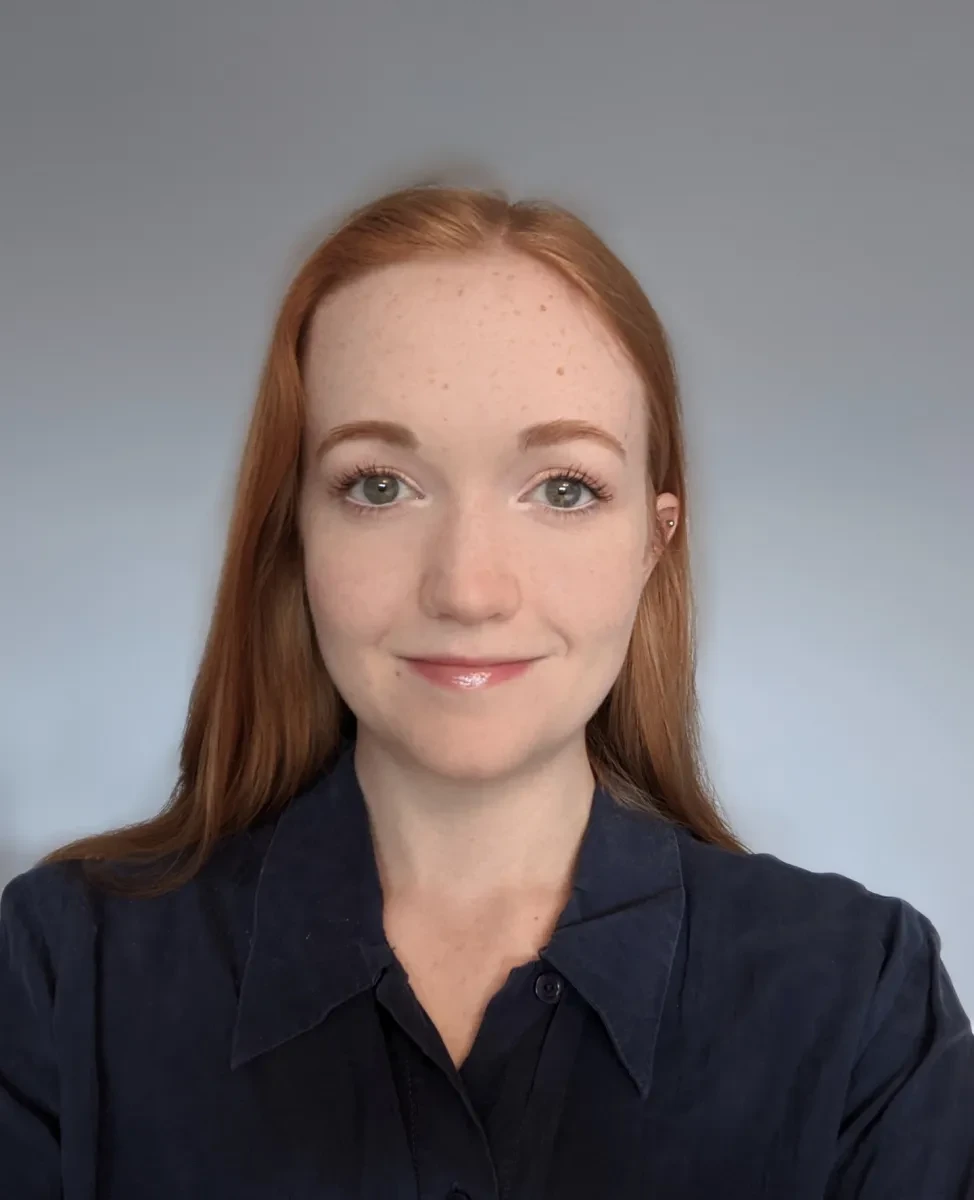 A smiling young woman with mid-length reddish brown hair