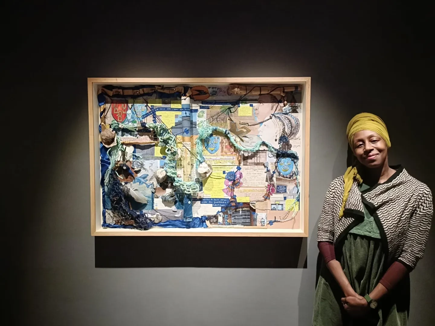 Artist Remiiya Badru stands next to a colourful collage style artwork