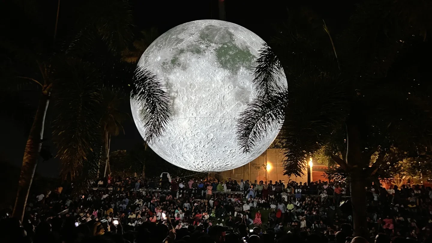 A large illuminated Moon above crowds in Kerala, India