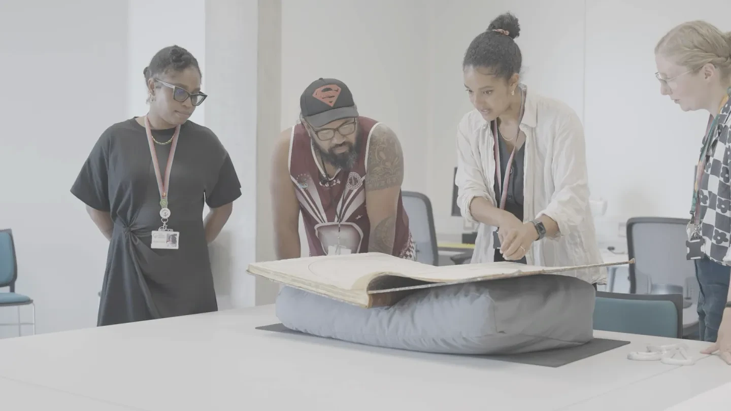 A group of people group over an historic book