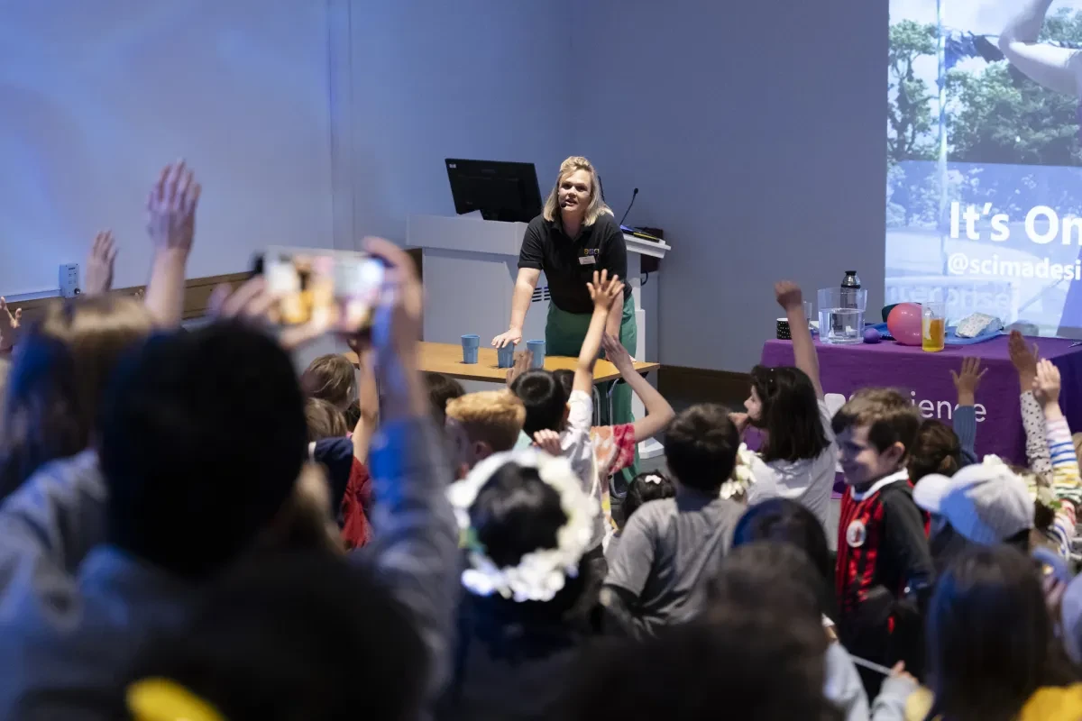 A woman giving a talk to children and adults in a lecture theatre