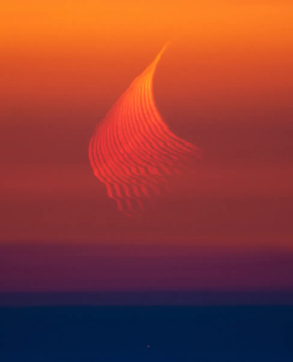 Photo depicting distorted refractions of the Moon in oranges and yellows against a golden sunset sky