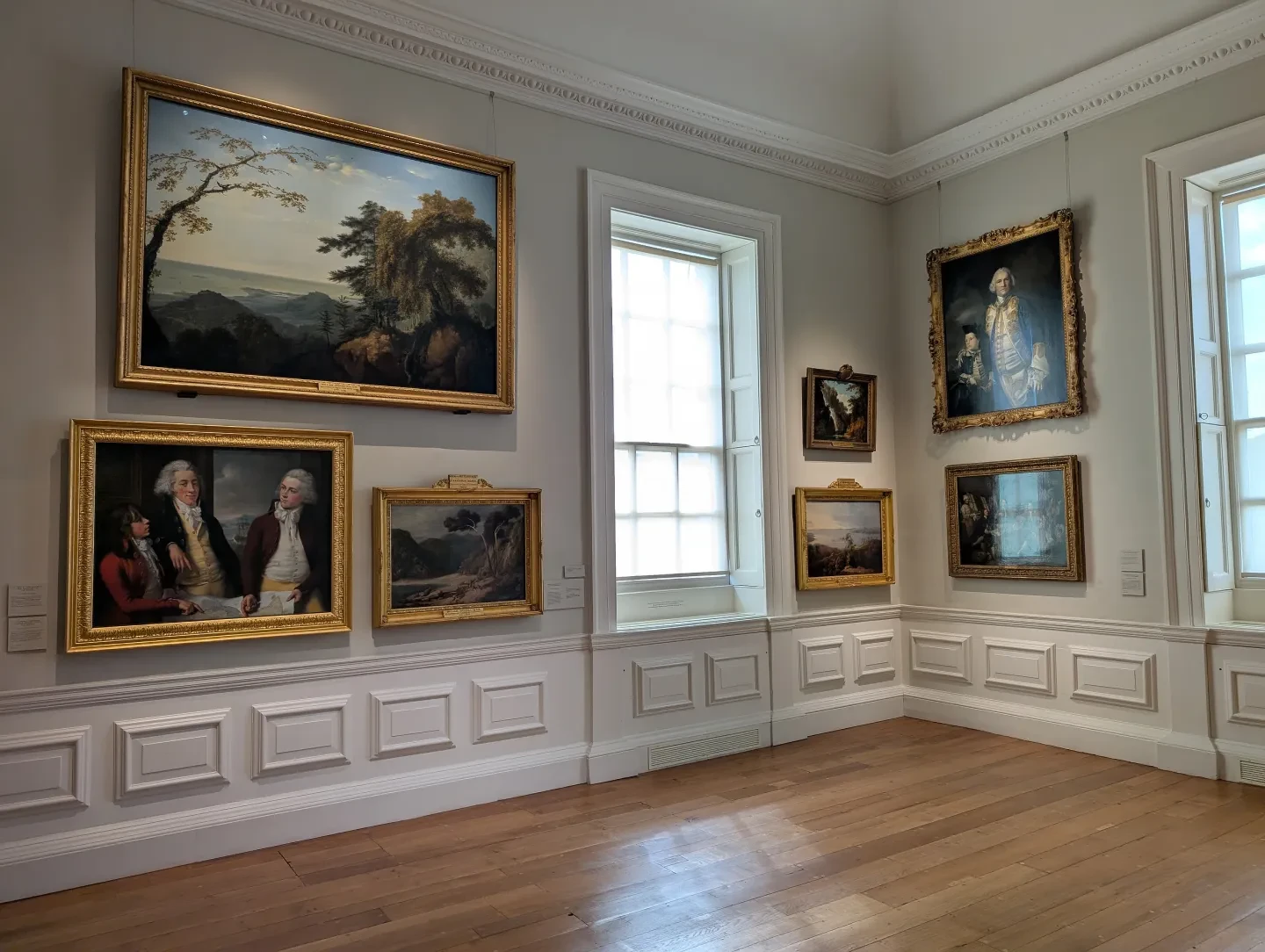 An art gallery with paintings of landscapes and naval officers from the 1800s